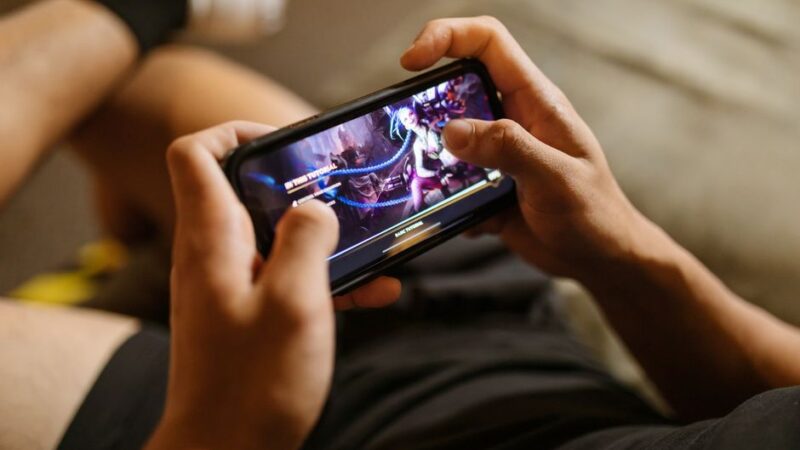 Persona jugando a un videojuego en un celular sujeto en horizontal