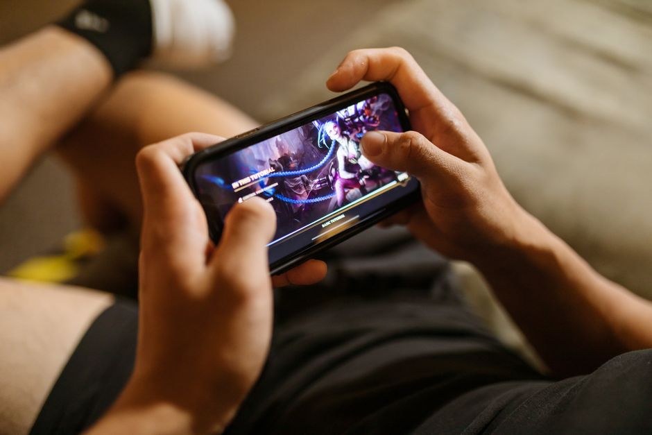 Persona jugando a un videojuego en un celular sujeto en horizontal