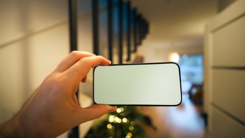 Mano sosteniendo un celular con la pantalla en blanco para revisar manchas